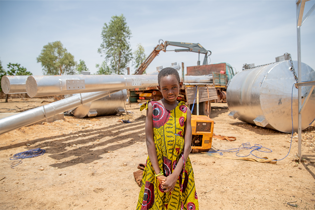 Egodine stands next to the drilling team working on digging a new borehole.