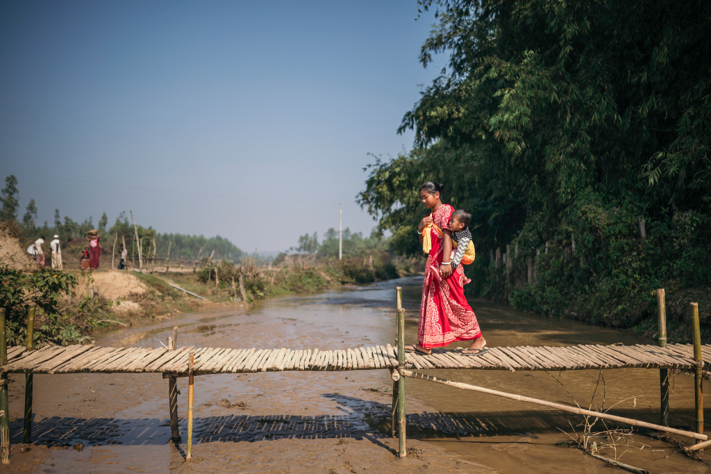 Kohima and baby Joy walk on a bridge